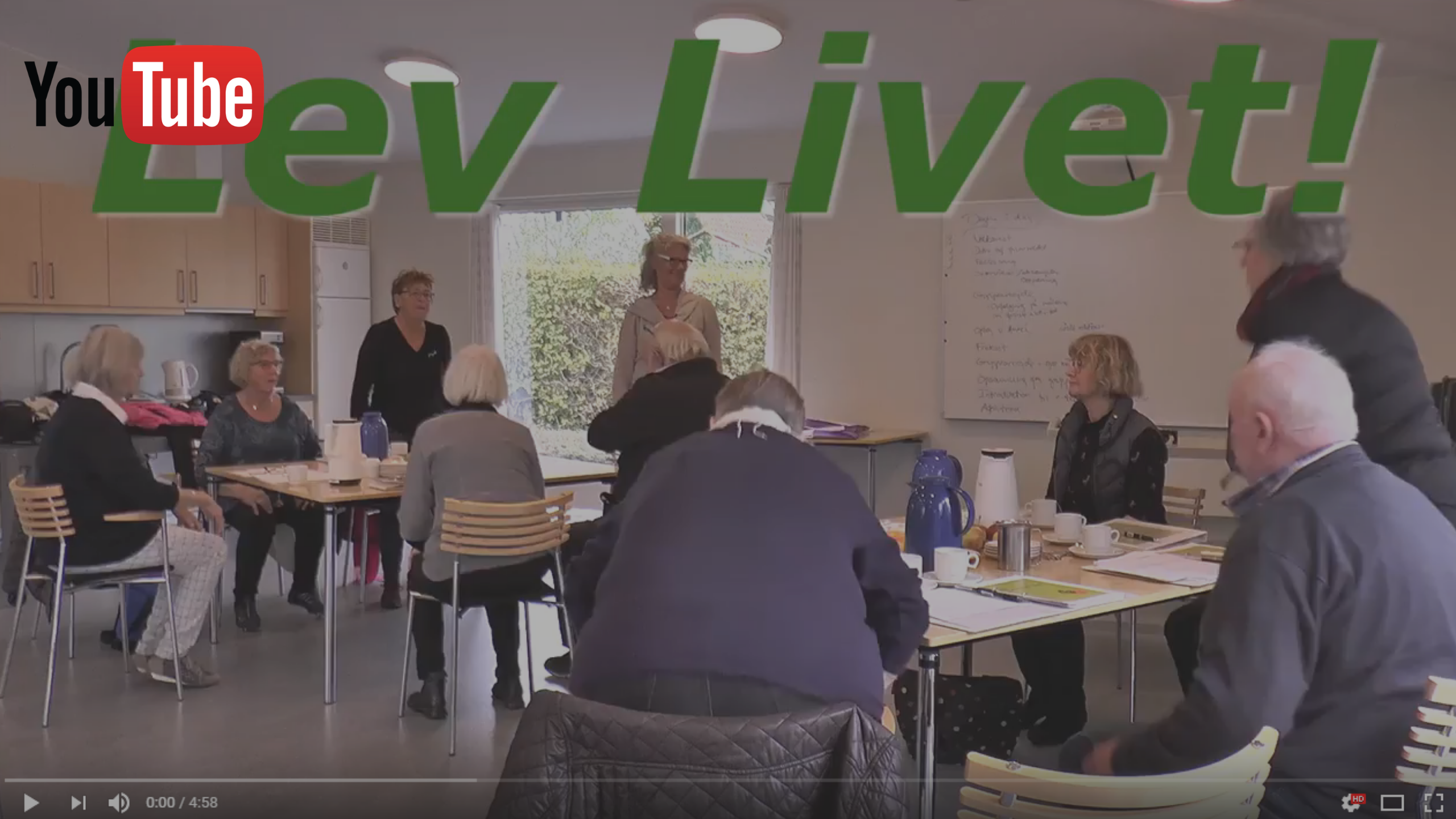 Billedet viser ældre mennesker siddende ved borde. Billedet er et link til en You-Tube-video fra første pilotforløb i LEV LIVET fra 2017.